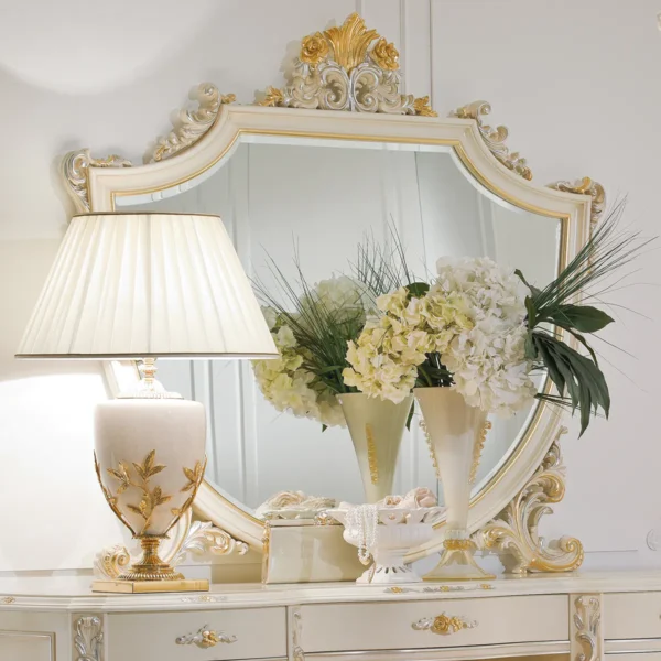 Eleonor large hand-carved wood mirror displayed above a dresser with a table lamp and flowers.