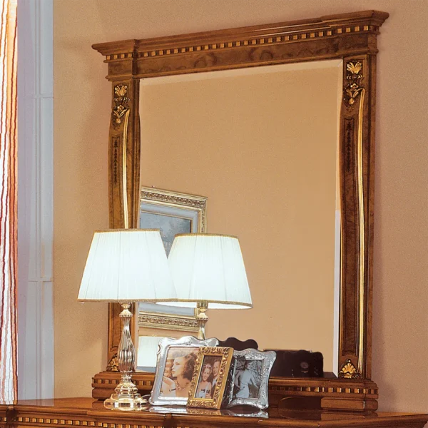 Elegant Regina wooden framed mirror with ornate detail, reflecting a luxurious lamp and photos on a polished dresser.