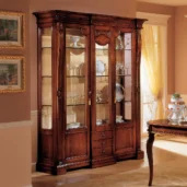 Elegant handcrafted Regina wood display cabinet with glass doors showcasing fine dining sets in a luxurious interior.