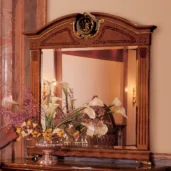 Elegant Senator mirror with intricate carvings, reflecting a floral arrangement, in a luxury villa interior.
