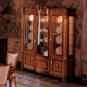 Luxurious handcrafted Senator display cabinet 3 doors with glass, showcasing elegant dishware in a richly decorated room.