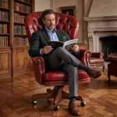Poltrona executive di lusso in pelle rossa con lavorazione capitonné, bottoni, borchie decorative e base girevole in legno