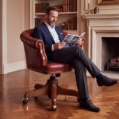 Luxury Chesterfield executive office chair upholstered in burgundy full grain leather with deep button tufting, solid wood swivel base and casters, handcrafted in Italy.