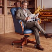 Luxury blue leather executive office chair with capitonné tufting, decorative studs, wooden details and wooden swivel base