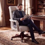 Poltrona executive in pelle bianca con schienale alto imbottito, braccioli sagomati e base girevole in legno